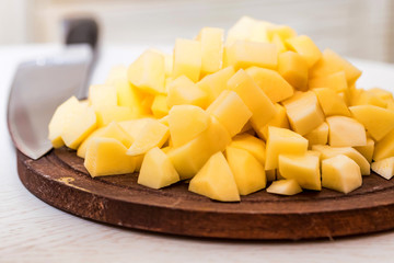 Pile of potato cut in pieces on wooden board