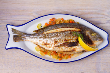 Grilled seabream on carrot, onion and celery stalks