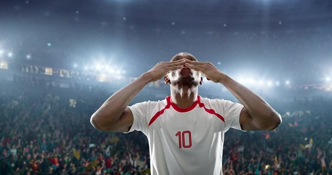 Happy soccer player celebrate a victory on a professional football stadium. He wears unbranded soccer clothes.