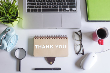 Thank You concept.Top view of white office desk with laptop,coffee,pen,magnifying glass,dried...