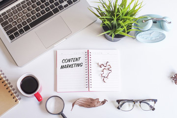 Laptop,coffee,spectacle,magnifying glass,green plant and notebook written with text CONTENT IS KING on white office desk table.Creative lay out view from top with copy space.