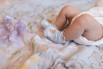 Obraz na płótnie Canvas Newborn baby on a blue background is lying on the bed. Blue socks. The legs of a newborn baby.