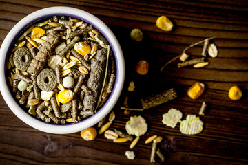 dry food for rodents in bowl wooden background top view