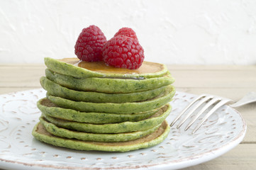 A stack of pancakes with syrup and raspberryi.