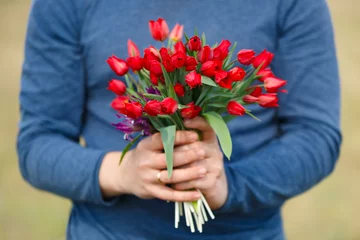 Poster de jardin Tulipe Flowers lazoriki. Bouquet of Red tulips in the hands of the men in blue clothing.