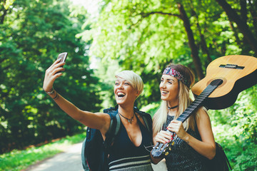 Obraz premium Two woman taking selfie along the road through woods