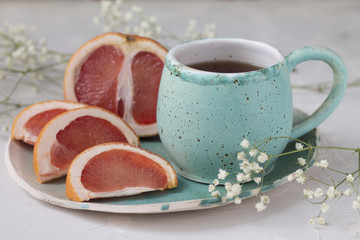 slices of juicy red grapefruit on blue green turquoise bowl mug Cup hot drinks tea coffee healthy Breakfast food meal, and little slices of dried tangerine and white dry flowers background texture