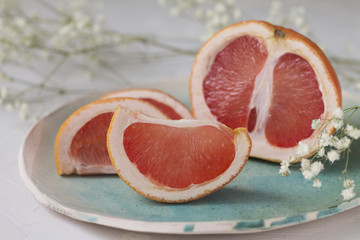 slices of juicy red grapefruit on blue green turquoise plate background texture