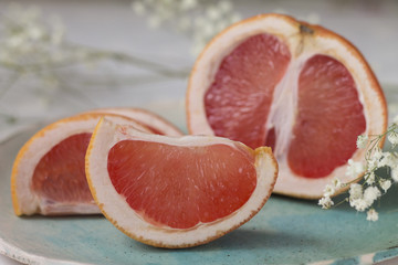 slices of juicy red grapefruit on blue green turquoise plate background texture