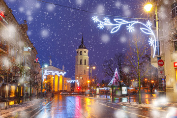 Fototapeta na wymiar Decorated and illuminated Christmas Gediminas prospect and Cathedral Belfry at snowy winter night, Vilnius, Lithuania, Baltic states.