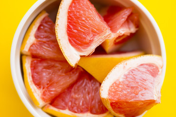 Healthy food concept, a bowl of sliced grapefruit on a yellow background with copy space, top view