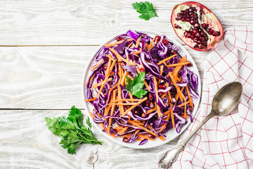 Red cabbage coleslaw with carrot pomegranate on white wooden background. Top view, copy space. 