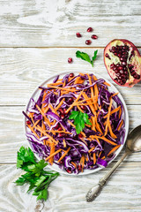 Red cabbage slaw with carrot pomegranate seeds on white wooden background. Top view, copy space. 