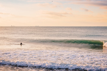 Fototapeta premium Surfer and perfect breaking barrel wave. Landscape with sunrise colors