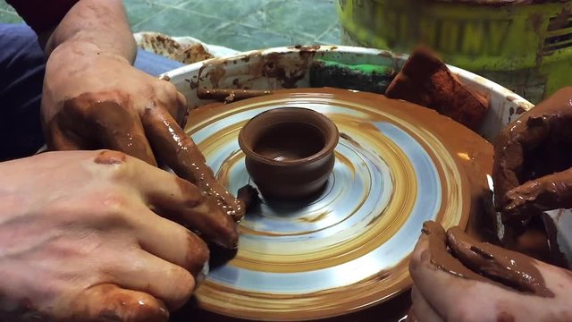 Pottery hands creating an earthen jar on a spin wheel.