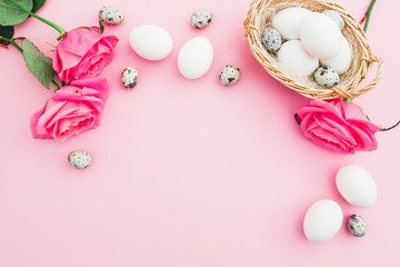 Easter egg and quail eggs in box and roses on pastel pink background, Top view