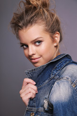 beautiful young girl with blond hair in cozy clothes posing in studio