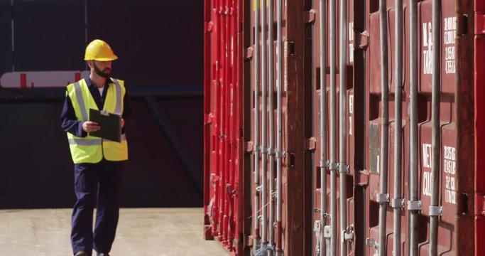 A young manager doing inspection rounds through an industrial harbor working on a digital tablet. Shot on RED Epic.