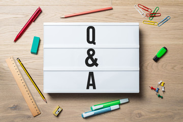 Q & A written on lightbox in office as flatlay