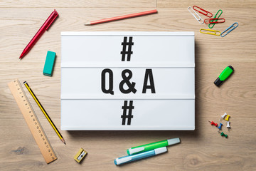 Q & A written on lightbox in office as flatlay