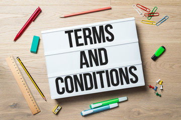 Terms and conditions written on lightbox in office as flatlay