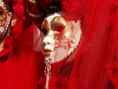 Sfilata delle mascere di carnevale a Piazza San Marco Venezia, figurante vestito di tulle rosso con maschera bianca e oro.