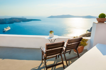 Fototapeta na wymiar Two chairs on the terrace with sea views. Santorini island, Greece at sunset