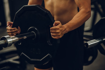 Male hand choosing a weight on a metal weights of bodybuilding equipment in a gym.
