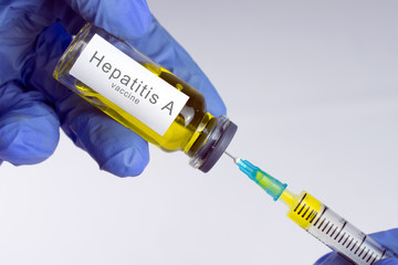 Hands in blue gloves are typing a yellow vaccine in a syringe. Hepatitis A vaccination concept. close-up, selective focus