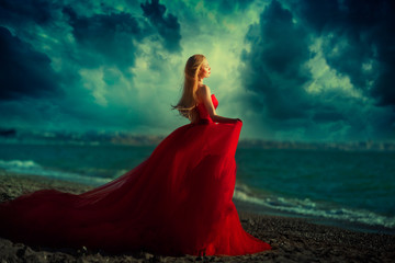 Beautiful girl by the sea. A woman in a red dress on the beach.