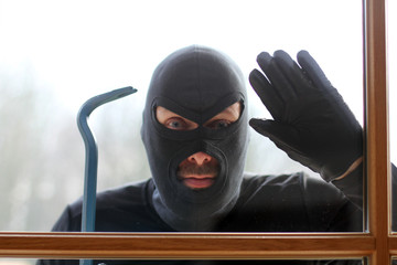 Einbrecher mit Brechstange am Fenster