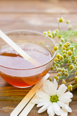 Set of sugaring essentials with natural honey, cinnamon sticks, and camomile on a natural dark wooden background