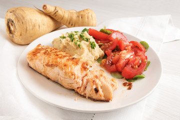 roasted salmon fillet with parsnip puree, tomato salad and parsley garnish, healthy diet meal on a white plate and a white table