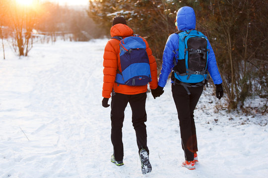 Picture from back of man and woman with backpacks in winter forest