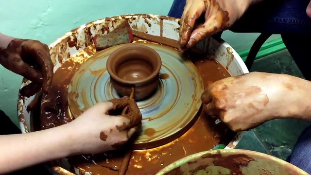 Pottery hands creating an earthen jar on a spin wheel.