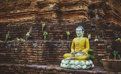 A statue of a seated Buddha against the background of an ancient brick wall. Thailand. Chiang Mai
