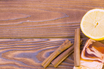 Dark natural wooden background with spa essentials: a bar of fruit soap, lemon and cinnamon sticks