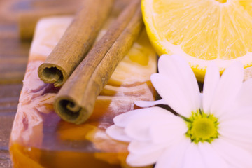 A close up of spa essentials with fruit soap, lemon and cinnamon sticks on a natural dark wooden background