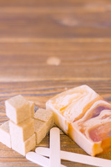 A set of spa essentials with a bar of fruit soap and brown sugar cubes on a natural dark wooden background