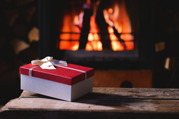 A present on a wood table in front of a fireplace
