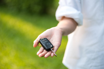house key in woman hand and green leaves background