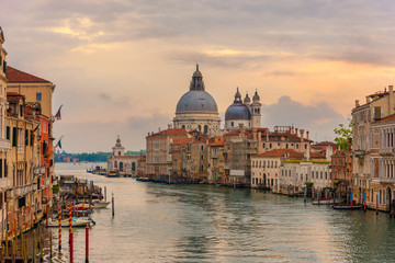 Naklejka premium Krajobrazowy widok zachodu słońca tradycyjnych gondoli na słynnym Canal Grande z zabytkową Bazyliką di Santa Maria della Salute w tle w romantycznym złotym wieczornym świetle o zachodzie słońca w Wenecji,