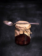 a small jar of strawberry jam and an iron spoon