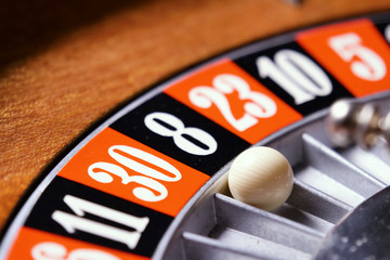 Macro shot of a roulette in a casino where the ball goes to the black number. People having bet and bet money may have won lost badges. Concept of: fate, gambling, luck, destiny.