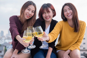 Group of asian friends drinking and having fun outdoor cheering at top roof.