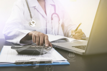 doctor working at office desk and calculator with computer.
