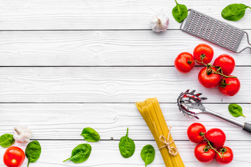 Naklejka na ściany i meble Cook spaghetti with tomatoes, garlic, basil. Italian recipe. White wooden background top view copy space
