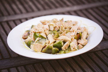 Salad with tuna and tomato served on a plate on a wooden table
