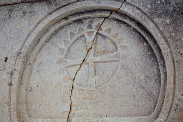 Closeup of a marble relief Maltese cross on a stone wall of an ancient Sicilian church.