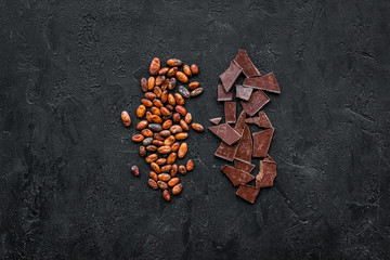 Roasted cocoa beans on black background top view copy space. Raw material for cocoa powder. African...